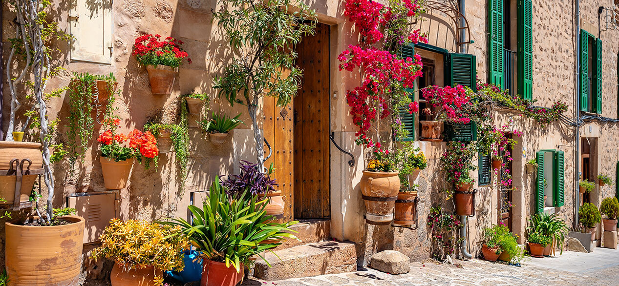 Hermoso edificio decorado en Valldemossa, Mallorca con flores y plantas en macetas delante