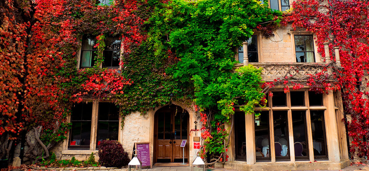 The exterior of Manor House Hotel and Golf Club with red and green leaves on the wall.